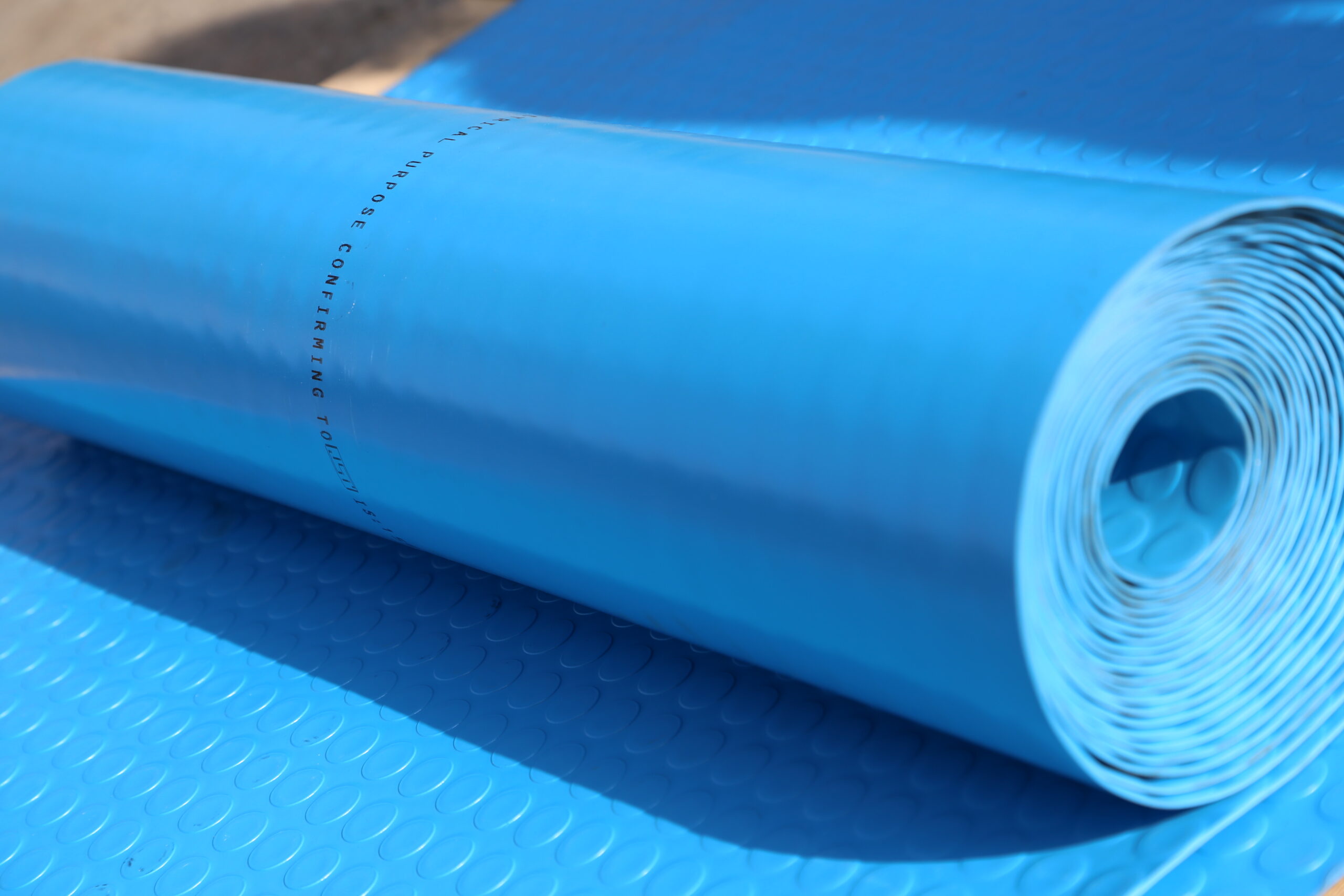 Electrical Insulating Mat. -A roll of blue electrical insulating mat, designed to provide high-voltage insulation and safety, displayed on a flat surface.